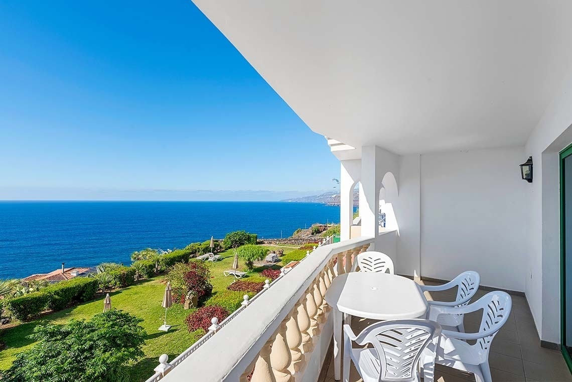 un balcon avec une table et des chaises avec vue sur l' océan