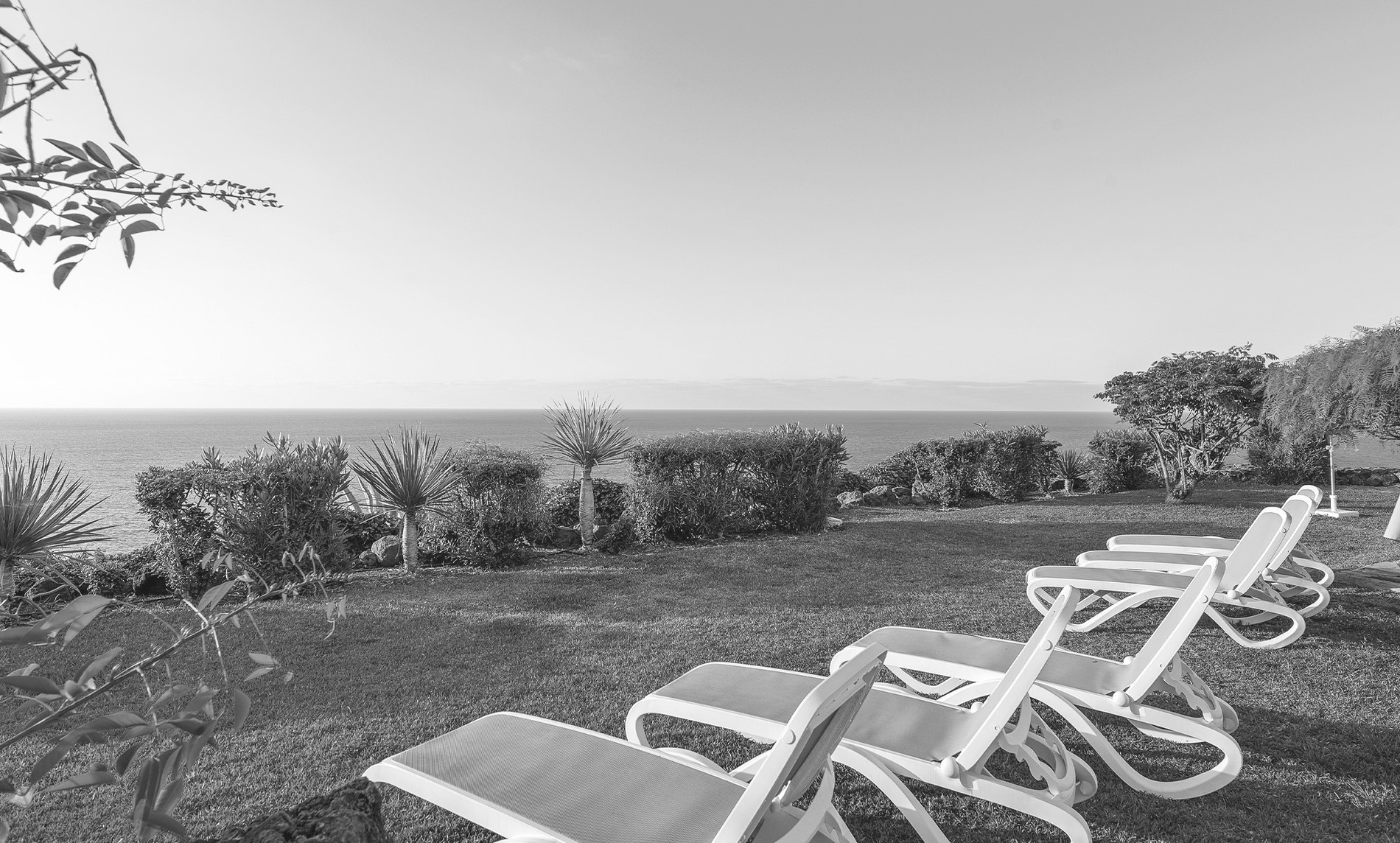 une photo en noir et blanc d' une piscine avec des chaises et des parasols=s1900