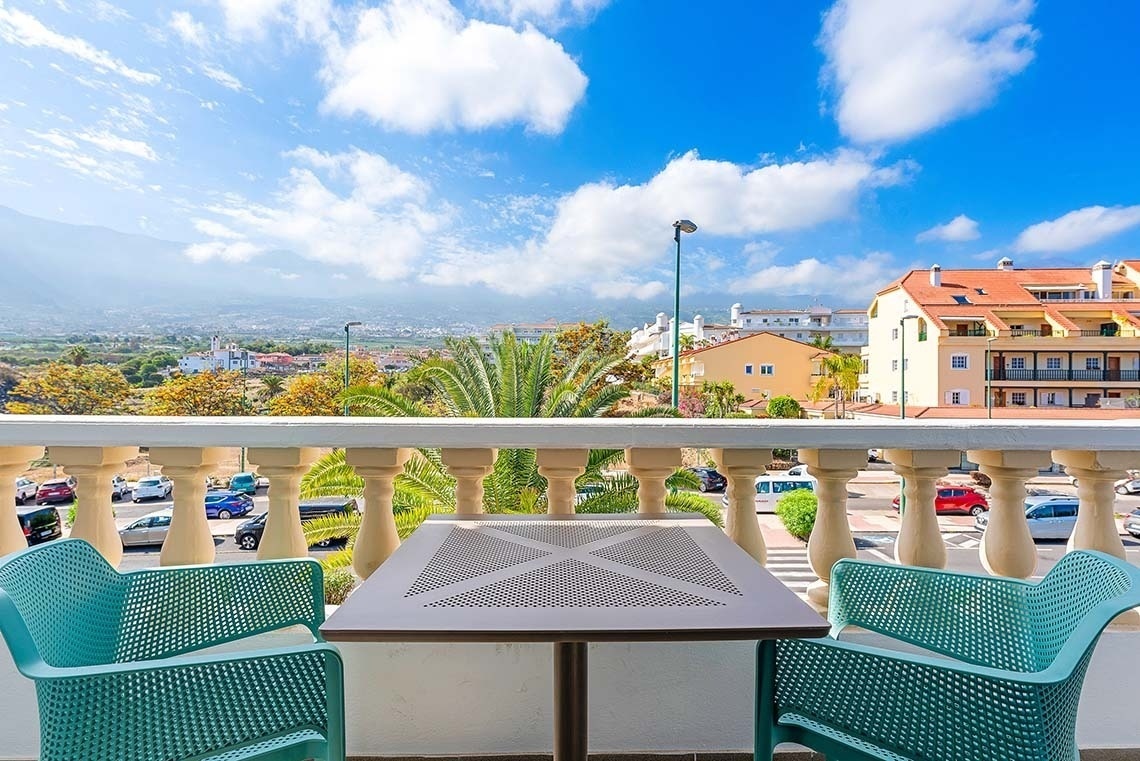 une table et des chaises sur un balcon avec une vue sur la ville