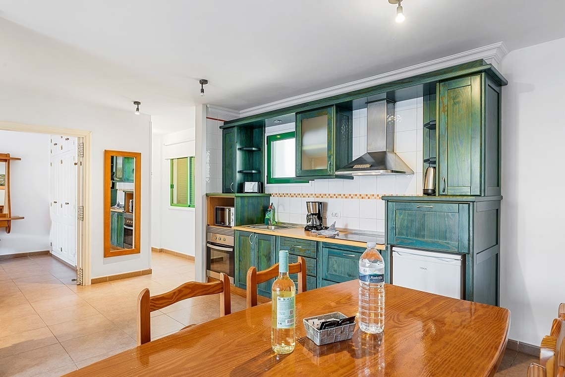 une cuisine avec des armoires vertes et une table en bois