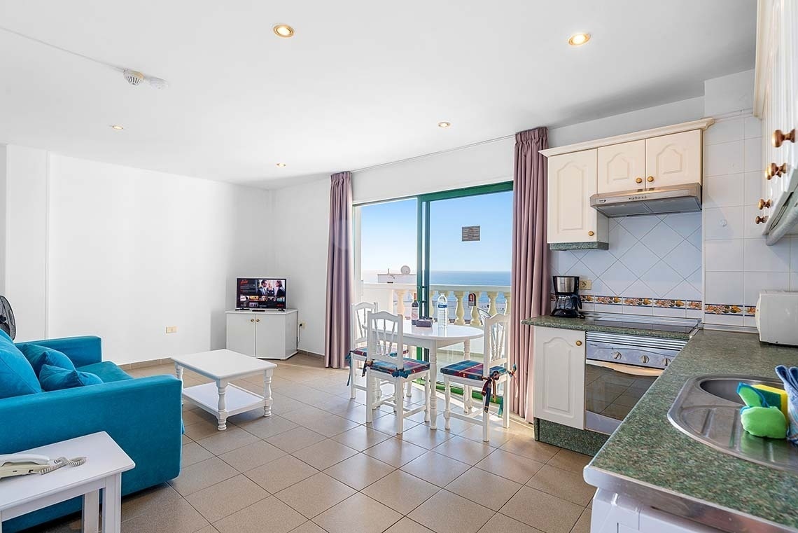 une cuisine avec un canapé bleu et une télévision