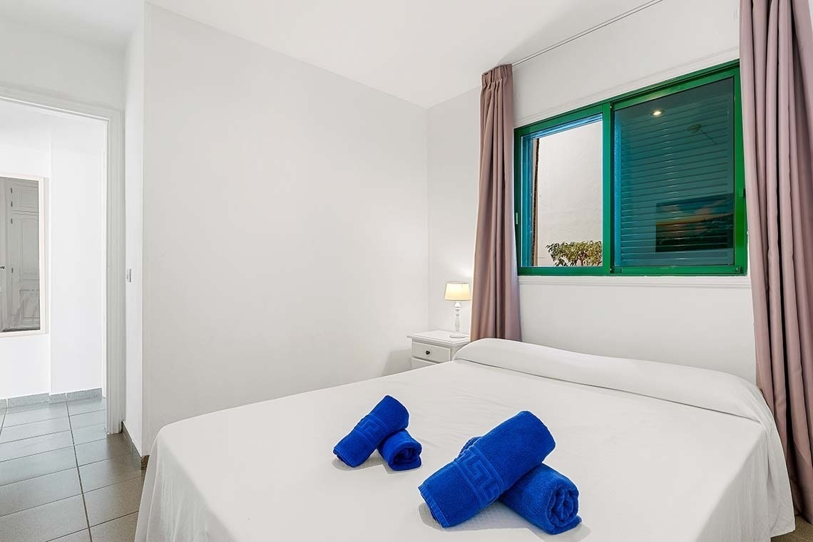 une chambre avec un lit et une fenêtre avec des serviettes bleues