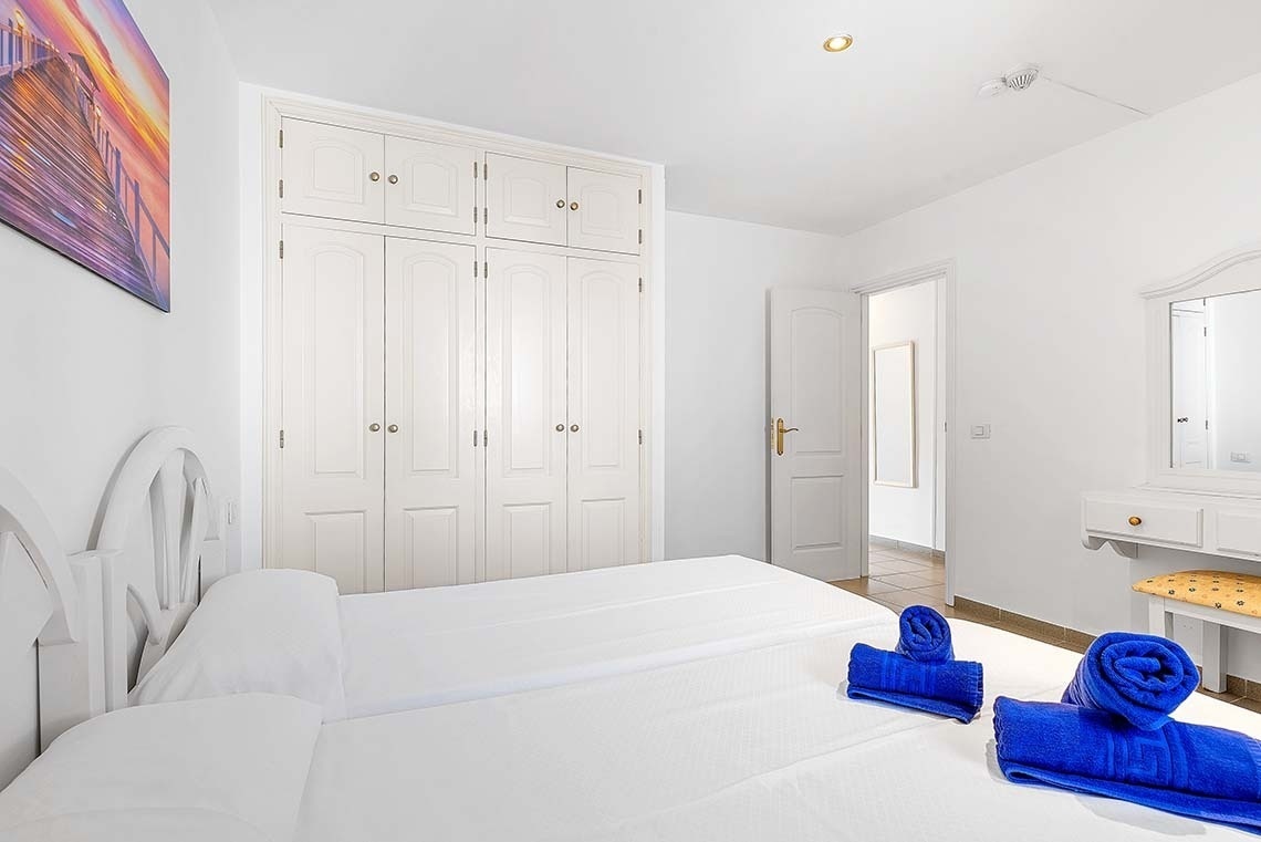 une chambre blanche avec un lit blanc et des serviettes bleues sur le lit