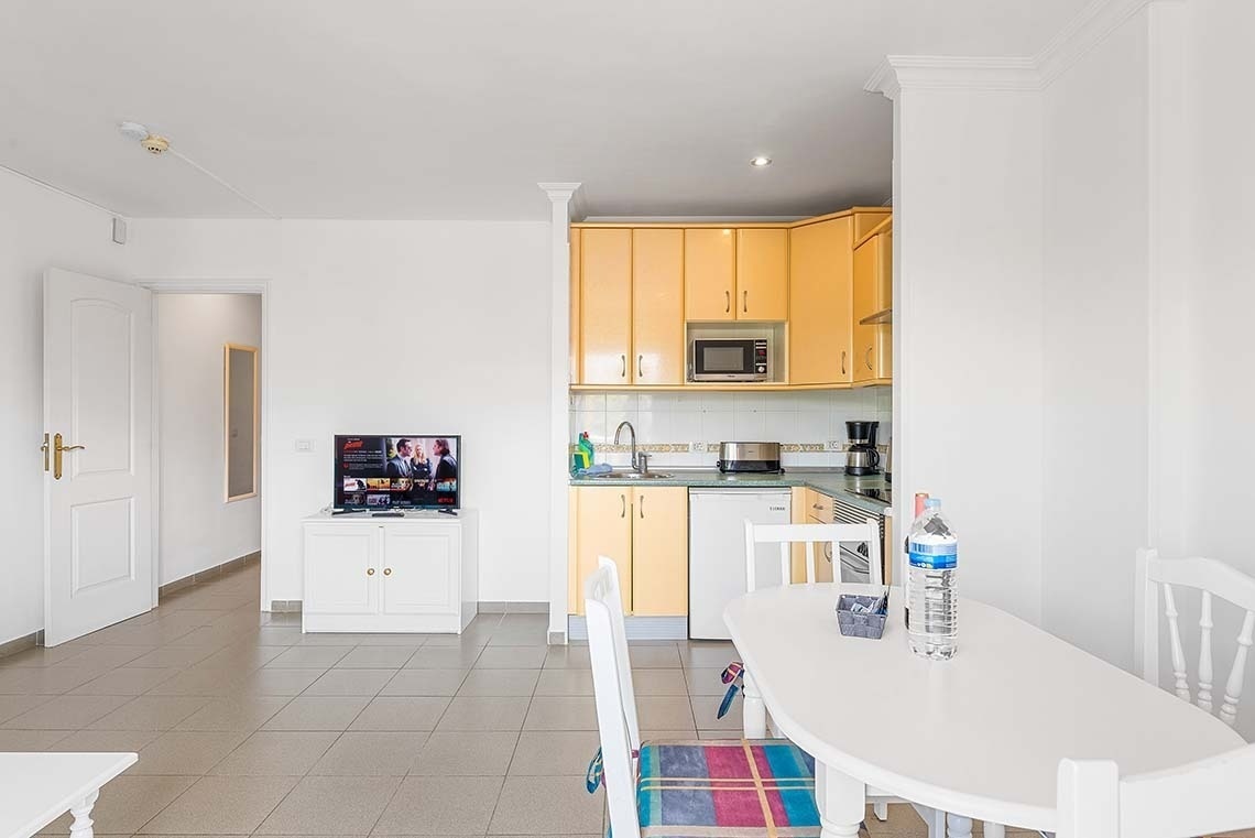 une cuisine avec des armoires jaunes et une télévision netflix