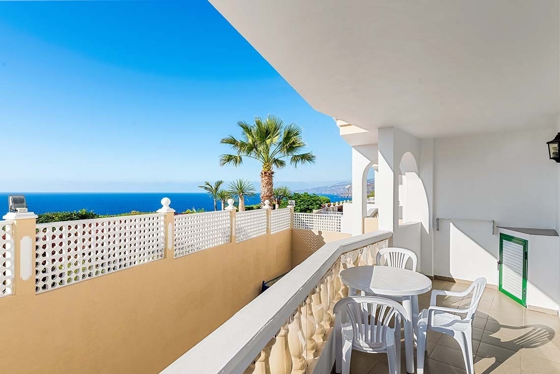 un balcon avec un parasol et une chaise longue