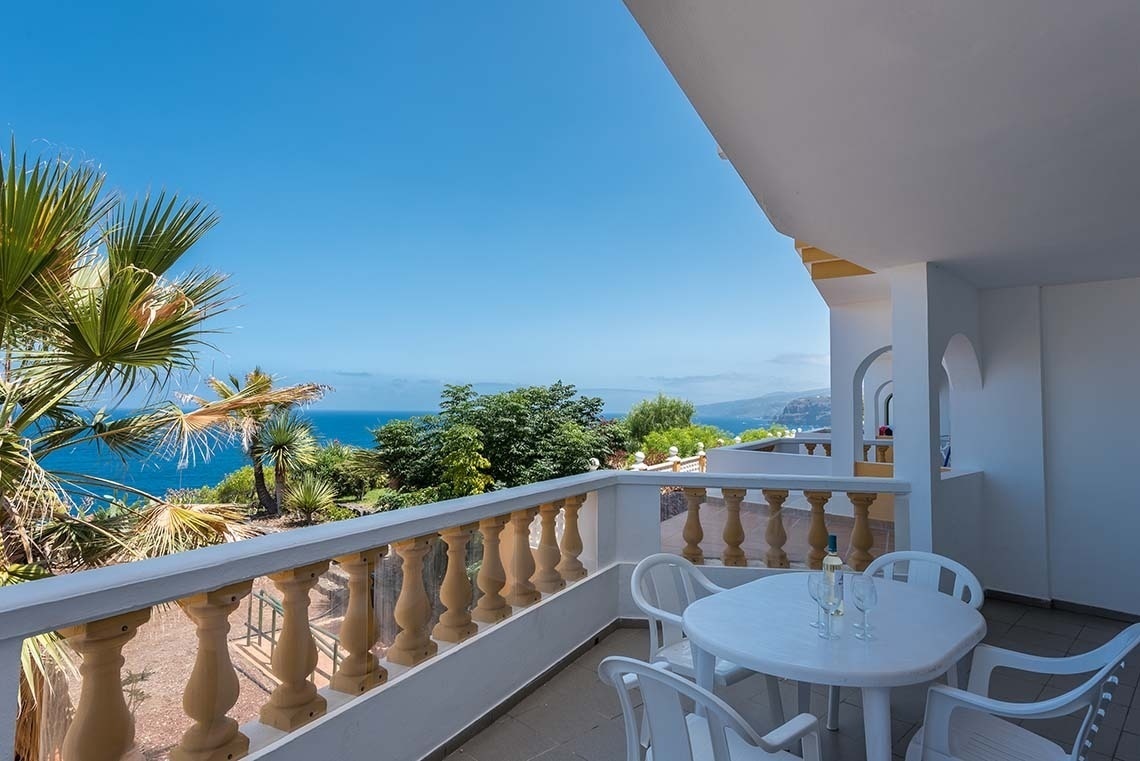 une table et des chaises sur un balcon avec vue sur l' océan