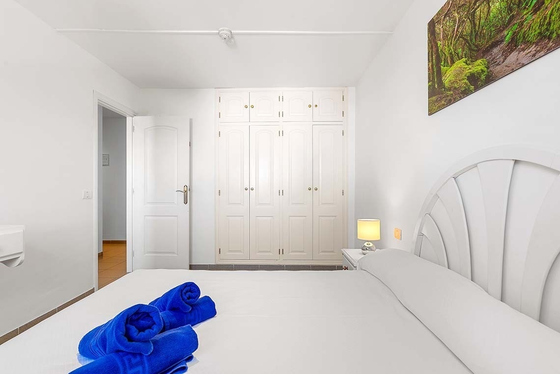 une chambre avec un lit blanc et des serviettes bleues sur le lit