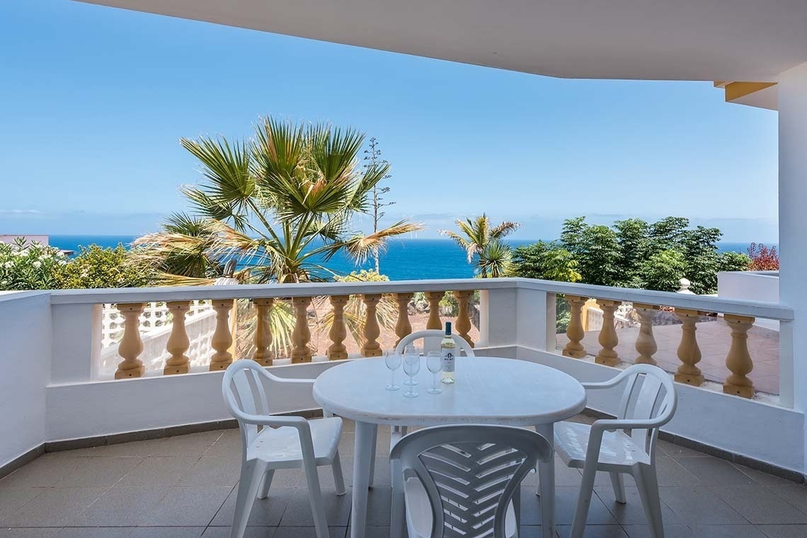 un balcon avec une table et des chaises et une bouteille de vin
