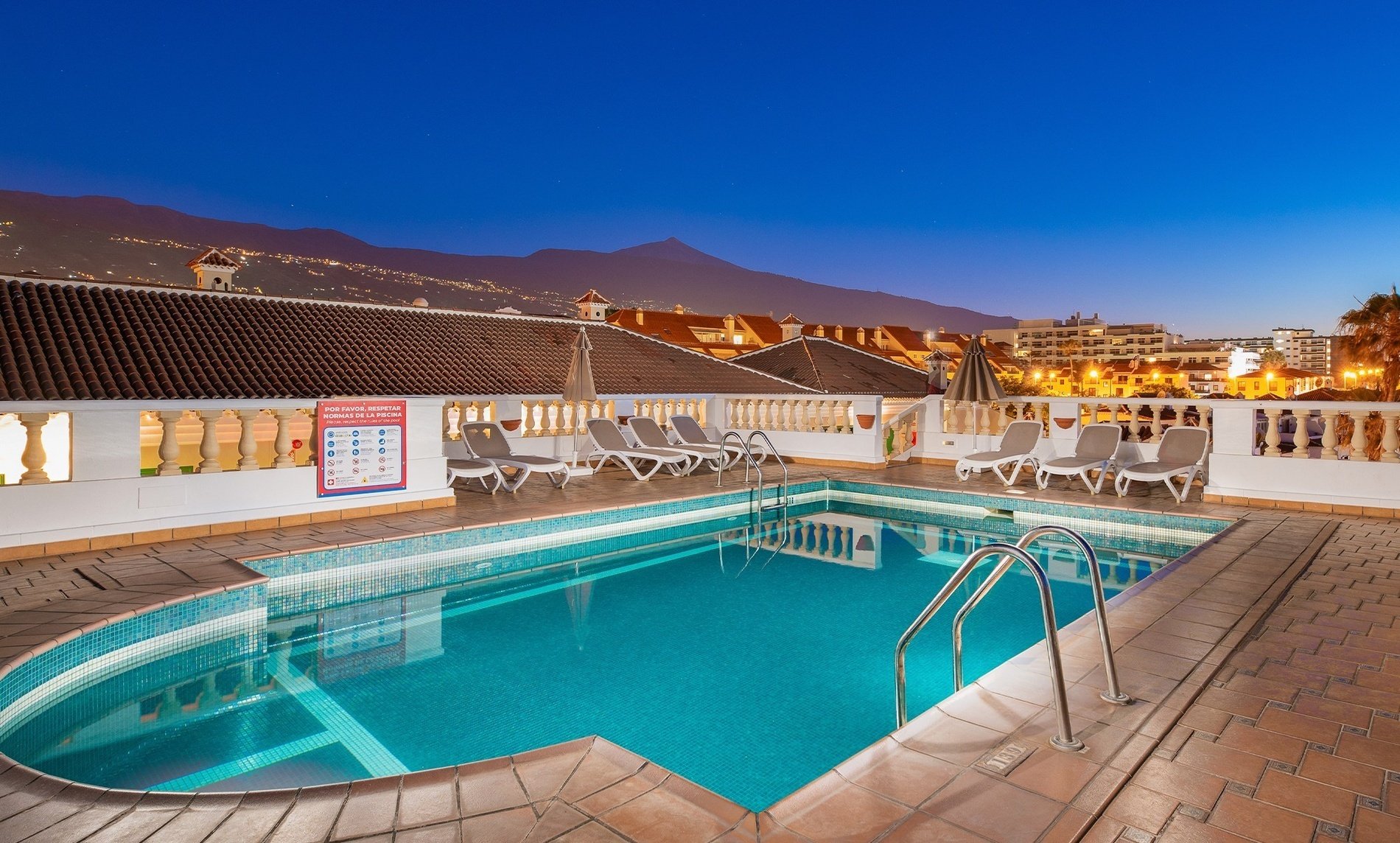 une piscine entourée de chaises et d' un panneau d' avertissement