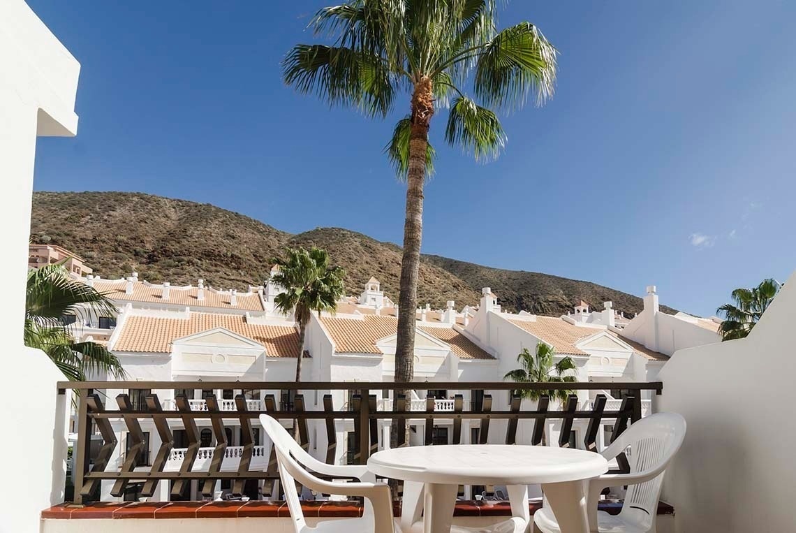 a balcony with an umbrella and a lounge chair