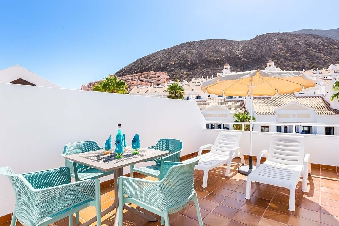 a balcony with a table and chairs and a yellow umbrella