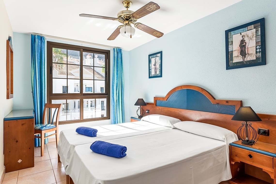 a bedroom with two beds and a ceiling fan