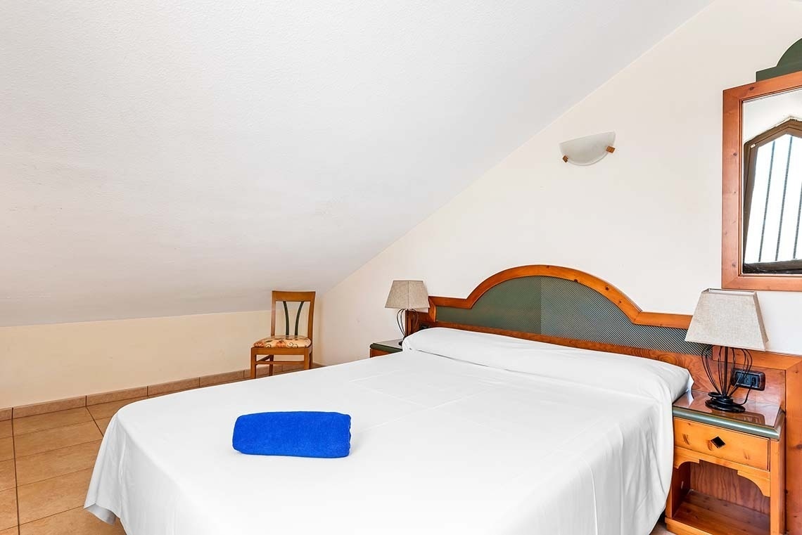 a bedroom with a white bed and a blue towel on it