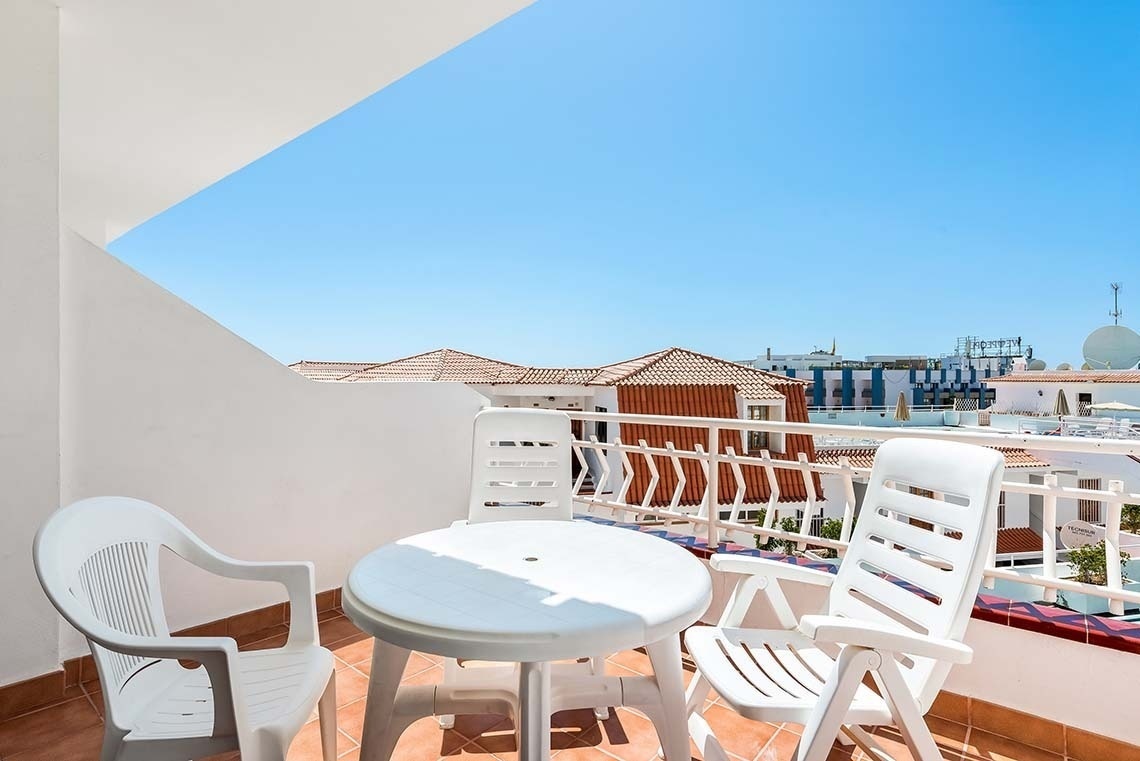 a white table and chairs on a balcony with a building in the background