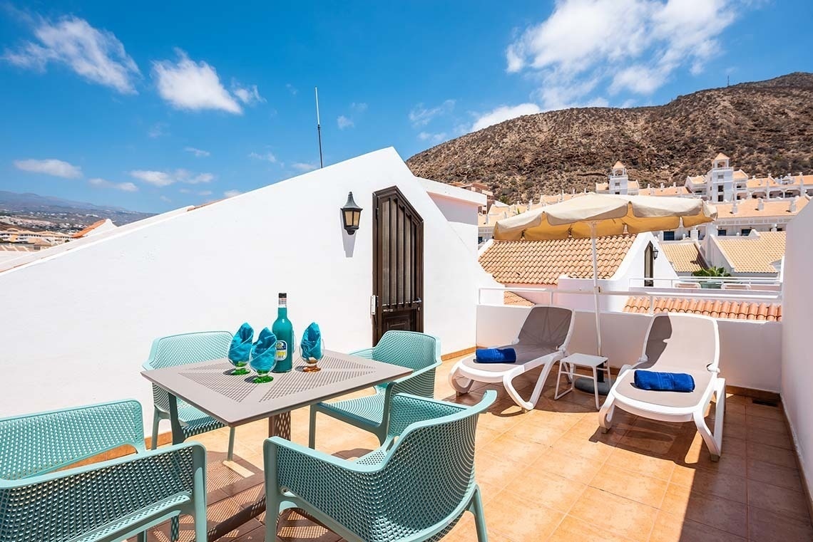 a balcony with a table and chairs and a mountain in the background