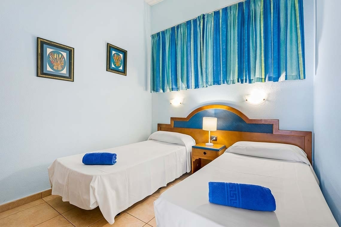 two beds in a hotel room with blue curtains