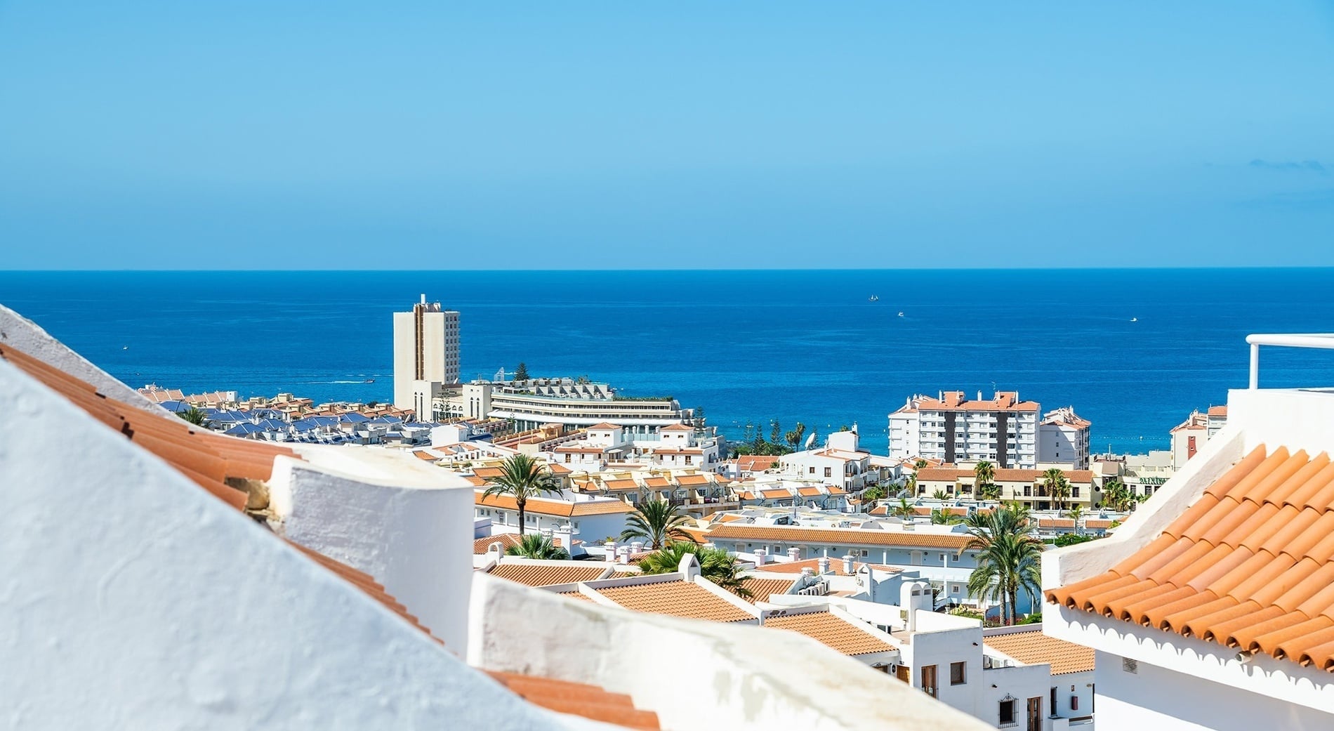 two lounge chairs under an umbrella with a hammock in the background