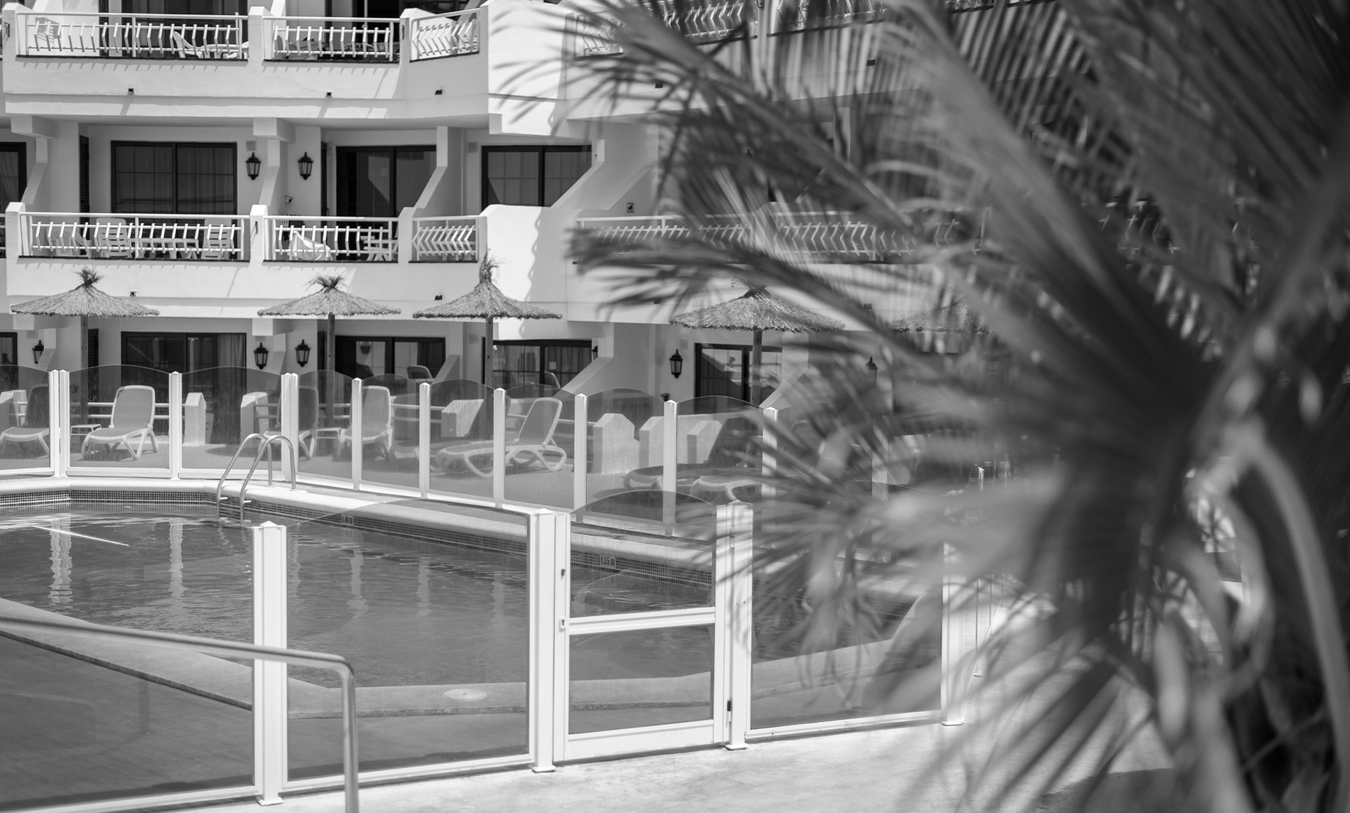 une photo en noir et blanc d' une piscine avec des chaises et des parasols=s1900