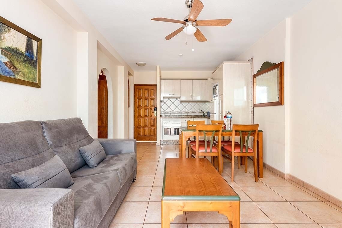 a living room with a couch a table and chairs and a ceiling fan