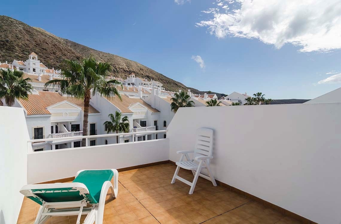 a white chair sits on a balcony overlooking a mountain