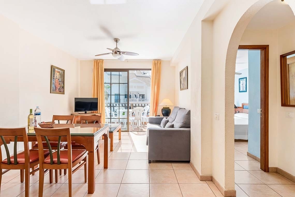a living room with a table and chairs and a ceiling fan