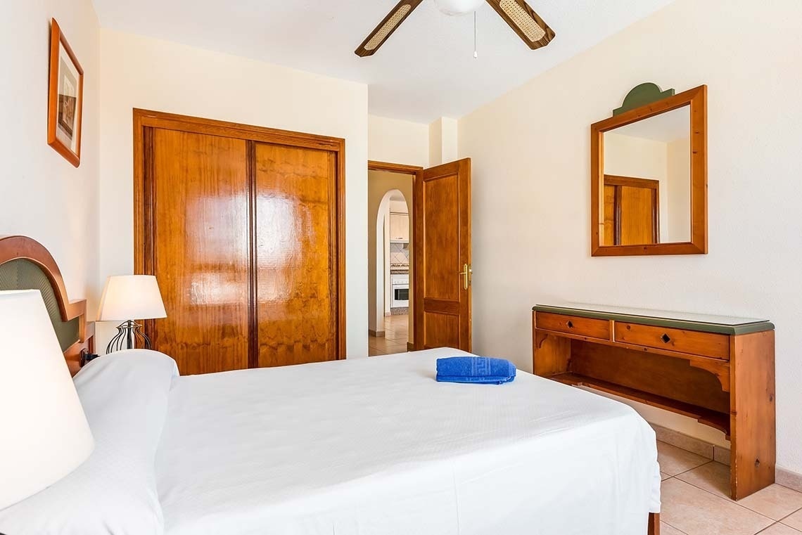 a bedroom with a bed a mirror and a ceiling fan