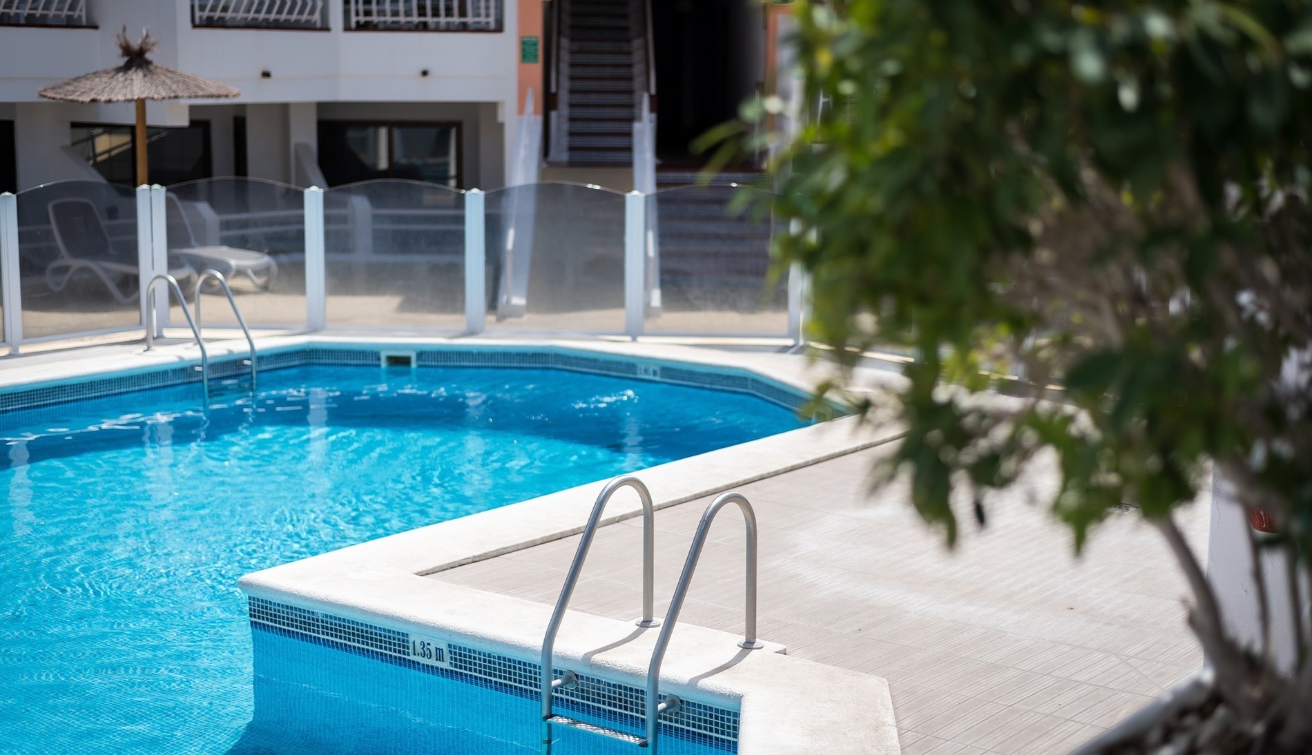 a swimming pool surrounded by chairs and potted plants