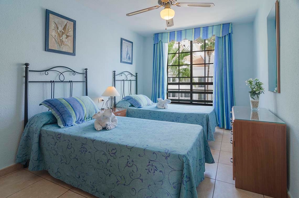 a bedroom with two beds and a ceiling fan