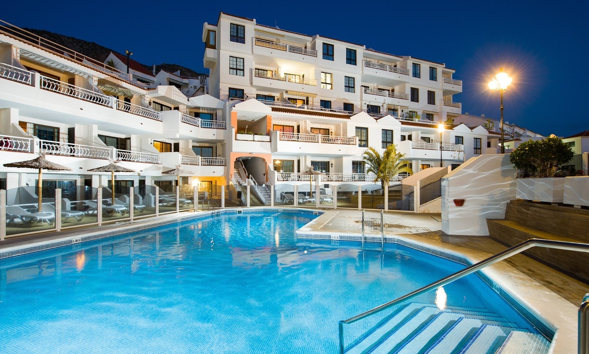 a large swimming pool in front of a building at night