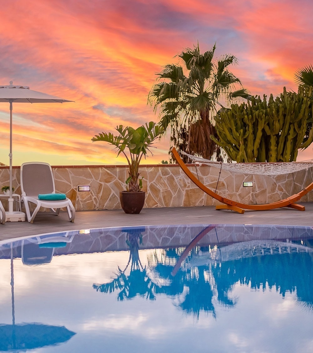 una hamaca se sienta junto a una piscina al atardecer