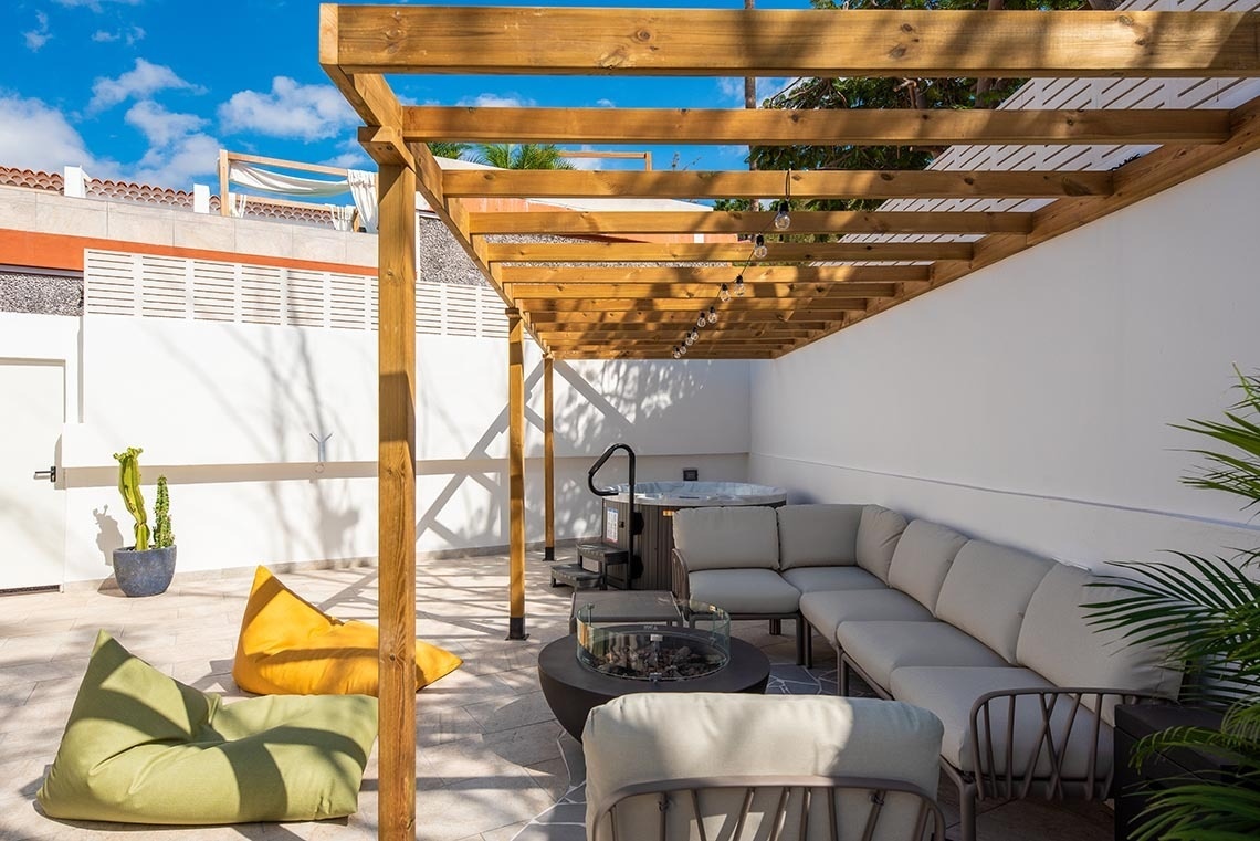 a patio area with a wooden pergola and a hot tub