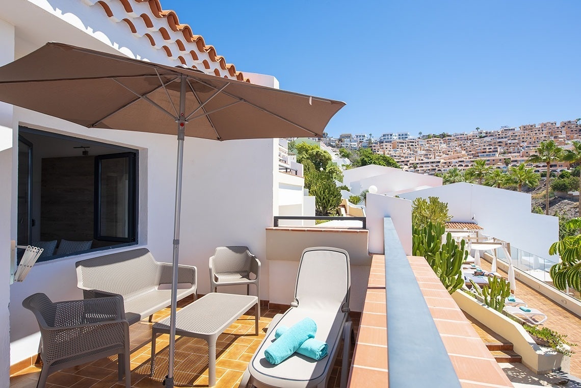 a balcony with a table chairs and an umbrella