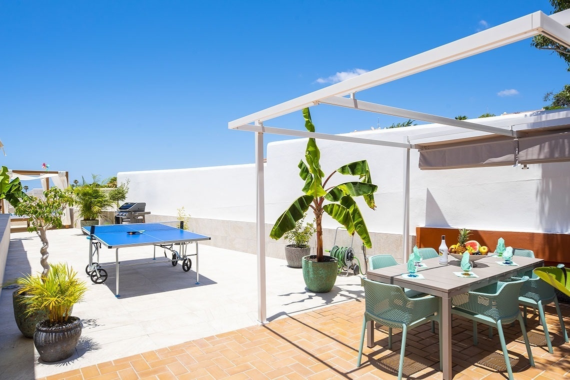 a patio with a table and chairs and a ping pong table