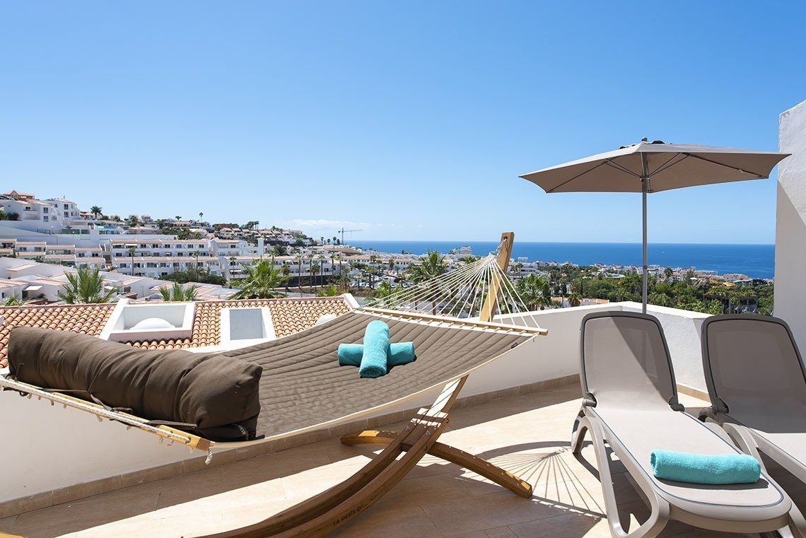 a hammock on a balcony with a view of the ocean