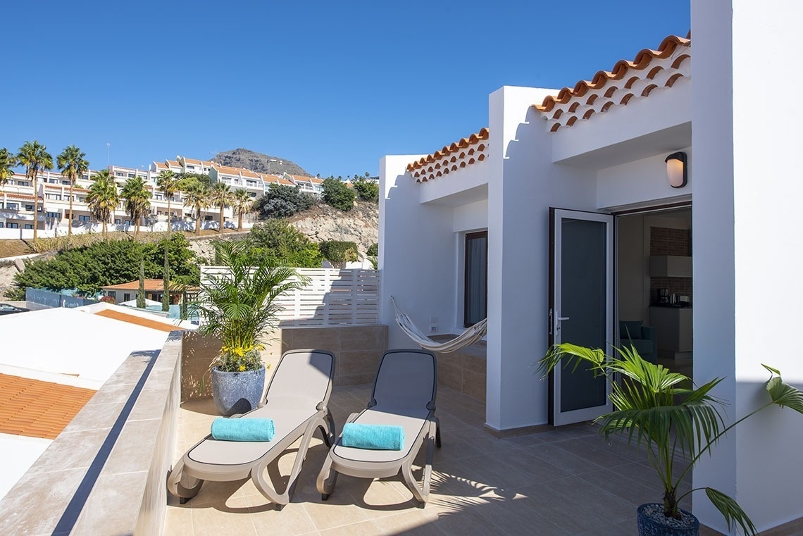 a balcony with two lounge chairs and a hammock
