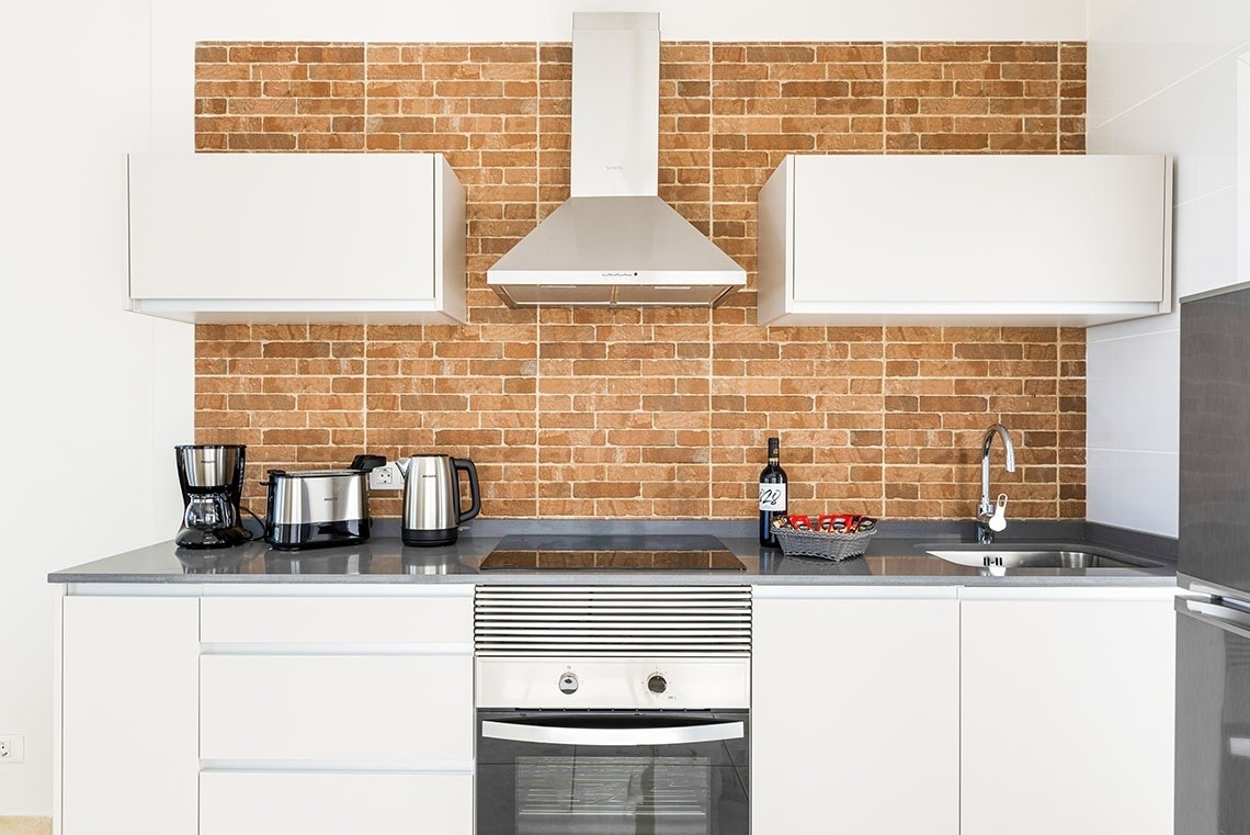 a kitchen with white cabinets and a brick wall