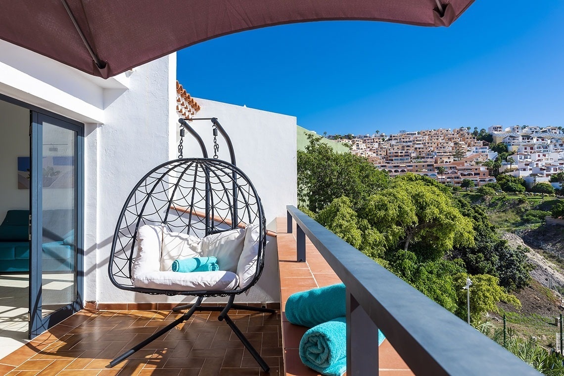 a balcony with a hanging chair and blue towels