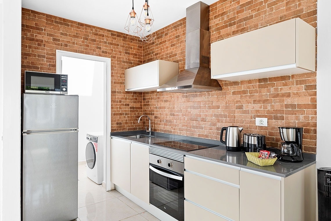 a kitchen with stainless steel appliances and a brick wall