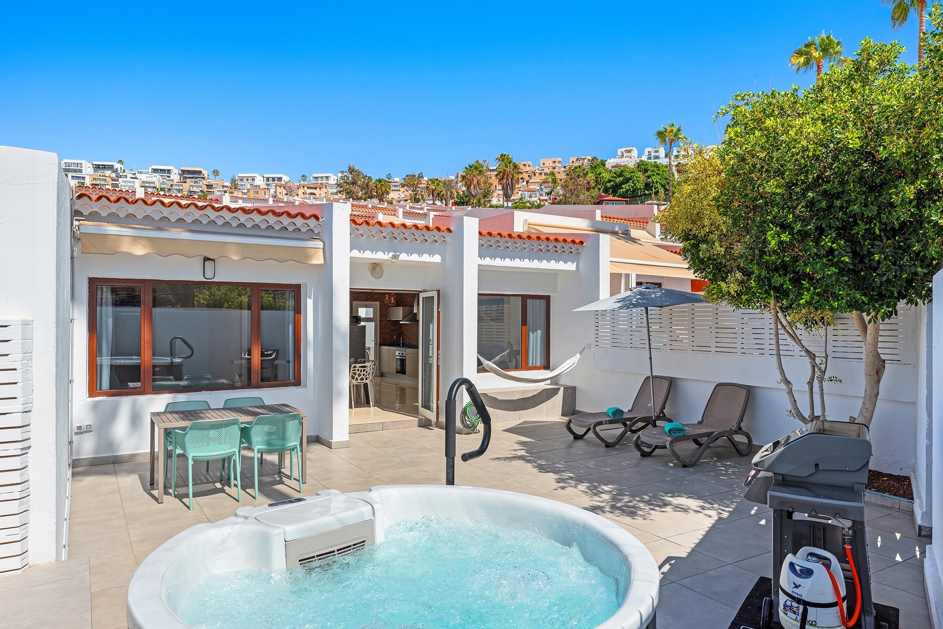 a patio with chairs and umbrellas and a grill