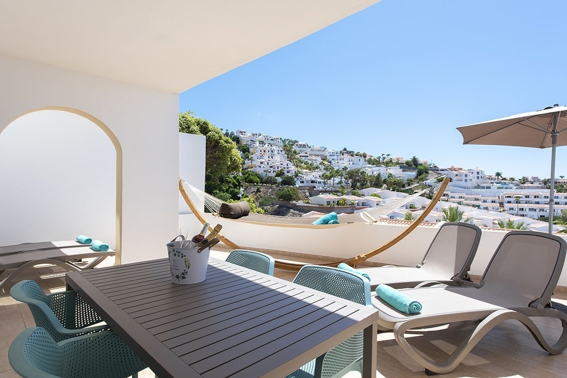 a table and chairs on a balcony with a hammock in the background