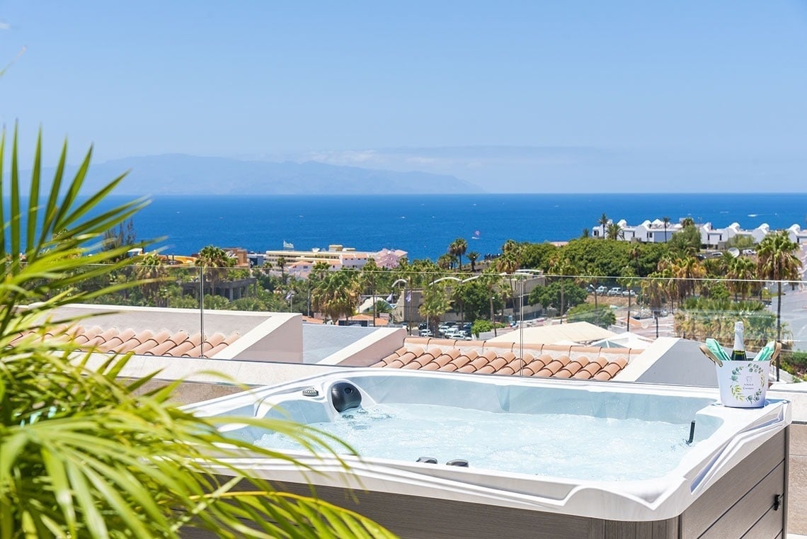 a hot tub with a view of the ocean and palm trees