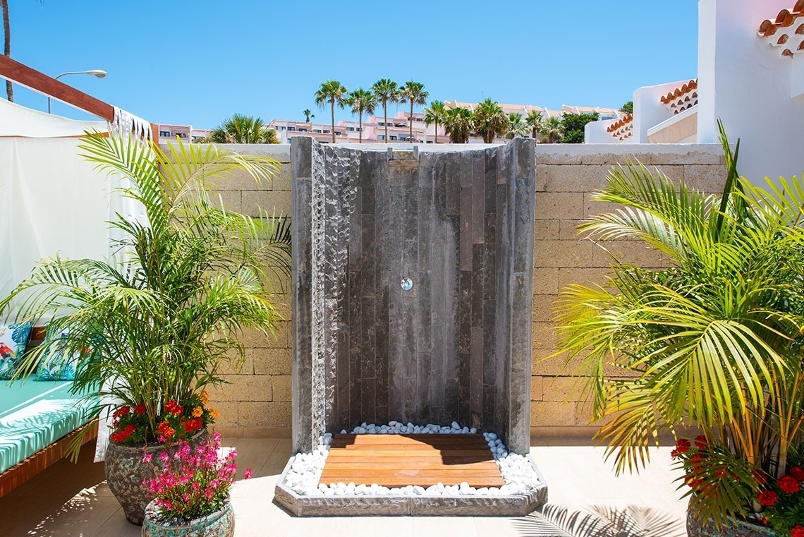 a outdoor shower with palm trees in the background