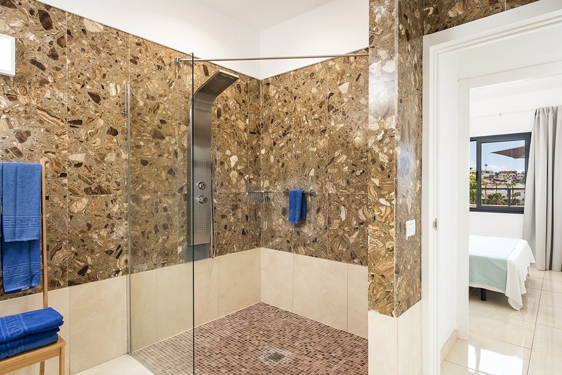 a bathroom with marble walls and a walk in shower