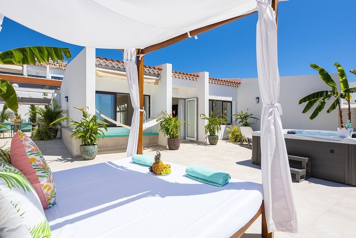 a canopy bed sits on a patio next to a hot tub