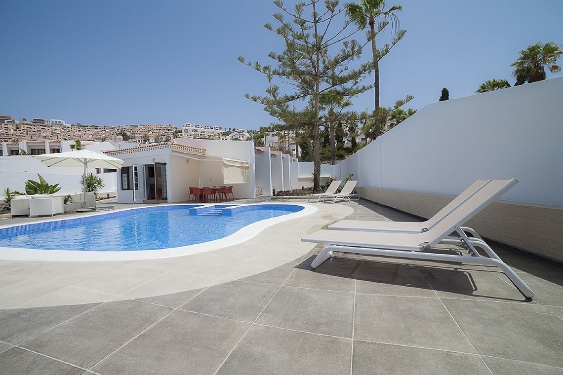 a swimming pool with chairs and umbrellas around it