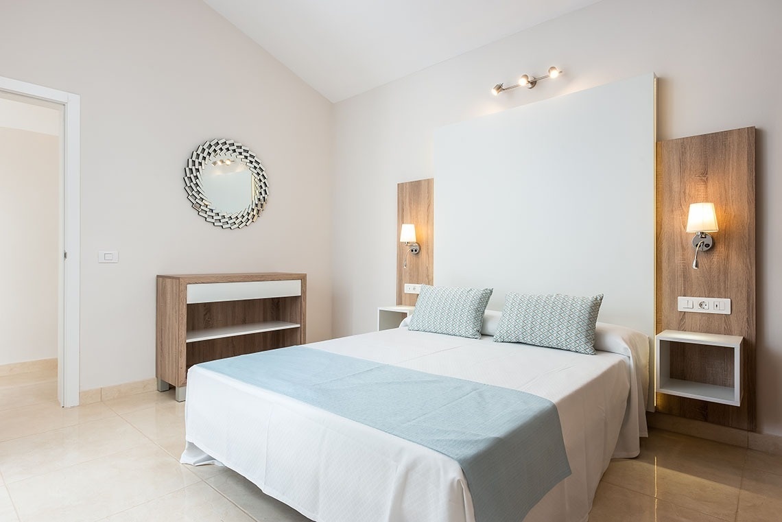 a bedroom with a bed and a mirror on the wall