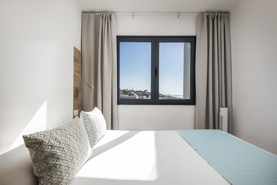 a bedroom with a bed and a window with a view of the ocean