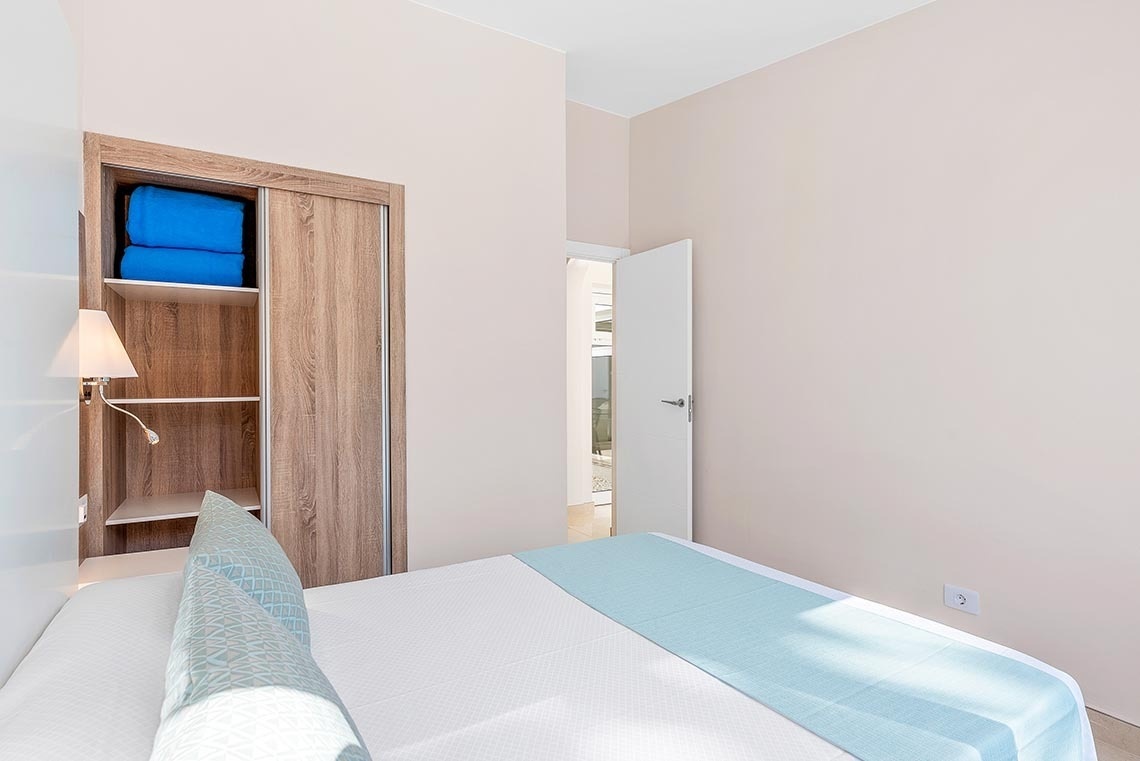 a bedroom with a bed and a closet with blue blankets in it