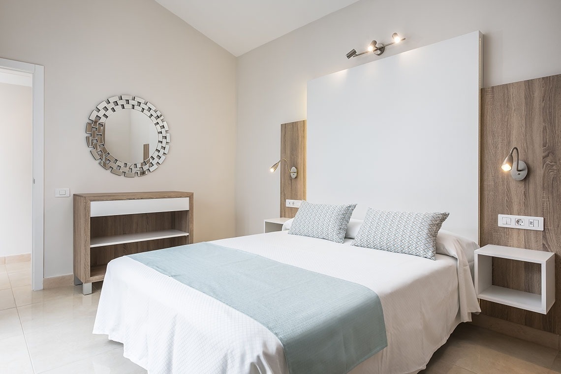 a bedroom with a bed and a mirror on the wall