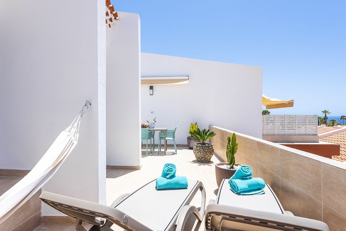 a balcony with two lounge chairs and a hammock